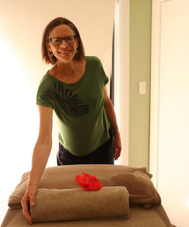 Julie Banks Massage Therapist in her Freshwater Beach clinic, leaning towards massage table